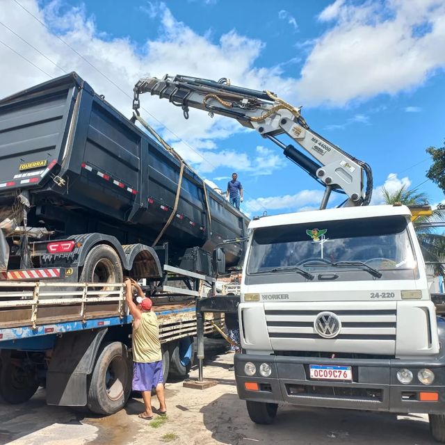 Caminhão munck içando um equipamento pesado sobre uma carreta
